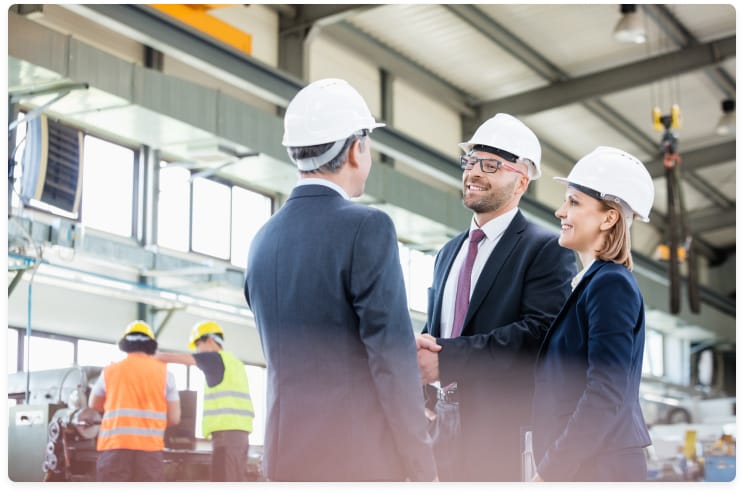 two gentleman shaking hands in factory
